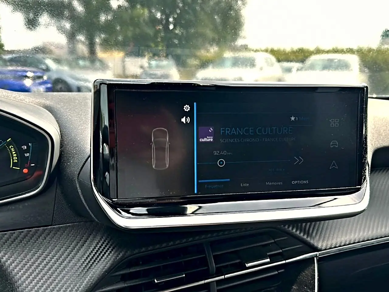 Écran tactile central allumé dans l’habitacle d’une Peugeot 2008 gris, vue de face côté conducteur.