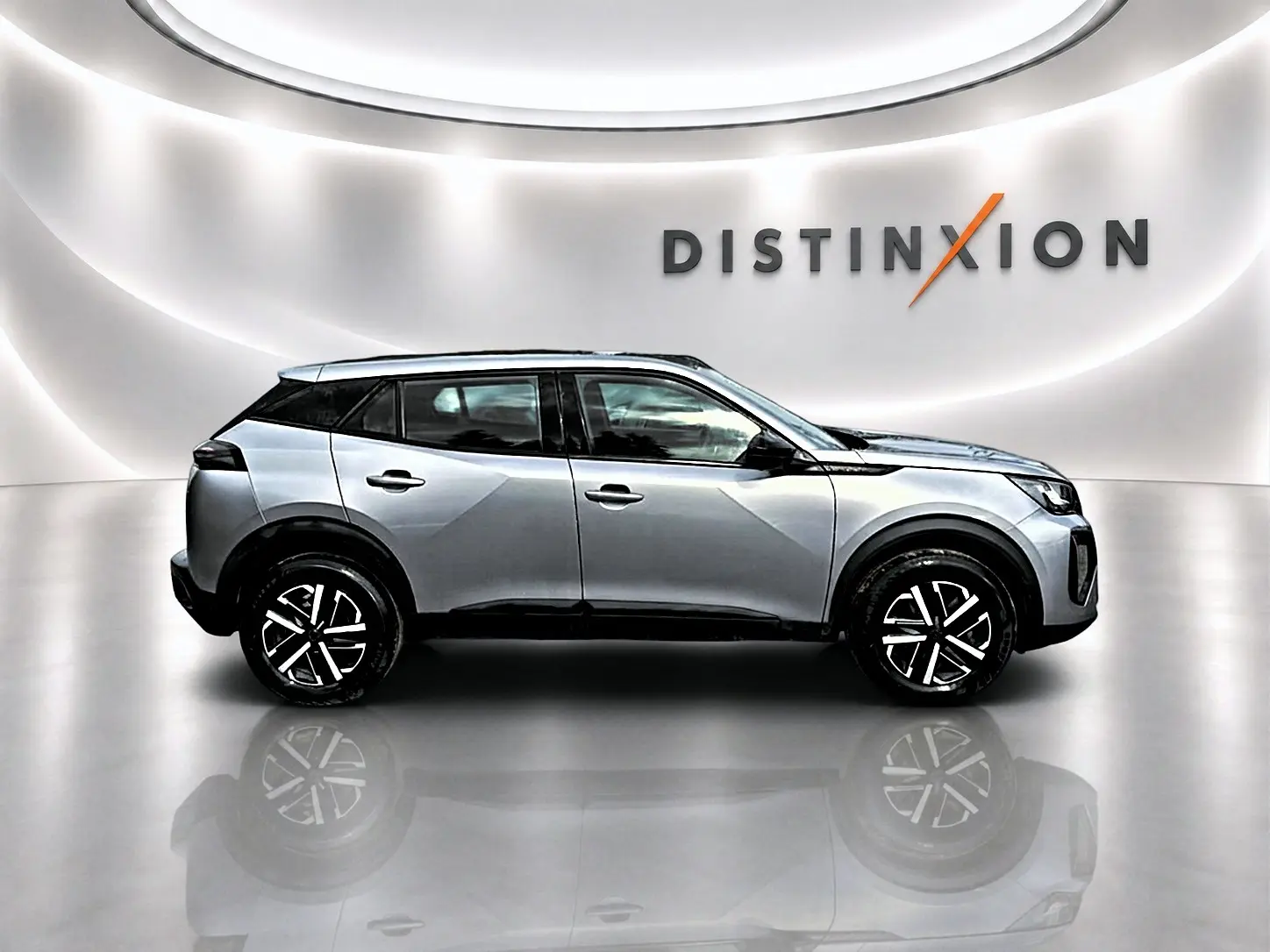 Peugeot 2008 gris en profil droit dans un studio lumineux avec logo Distinxion en arrière-plan.