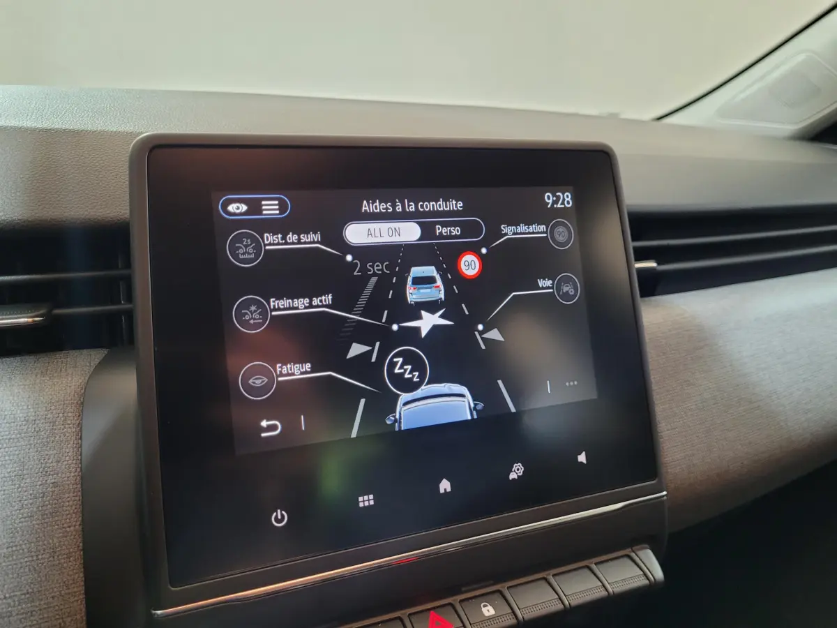 Écran tactile central de la Renault Clio gris foncé 2025 montrant les aides à la conduite et alertes sécurité.