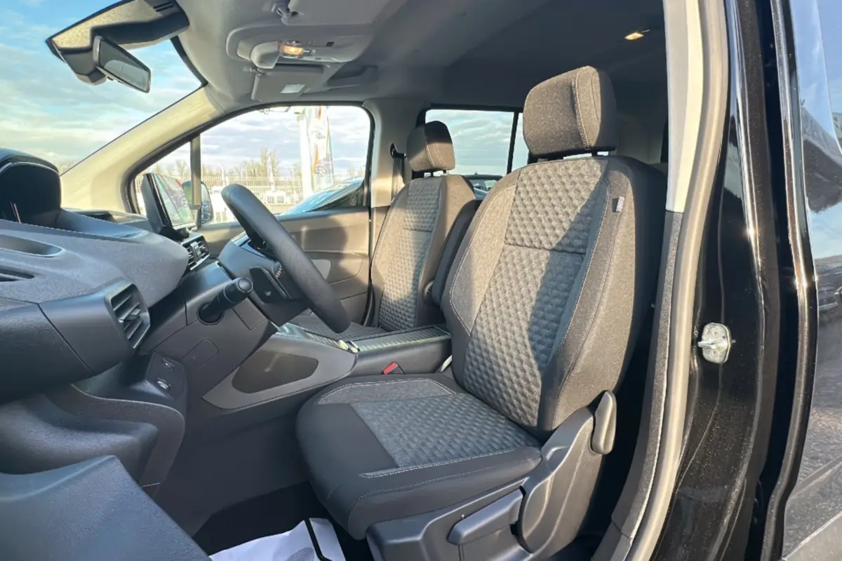 Vue intérieure côté gauche du Peugeot Rifter 2025 noir perla nera, montrant les sièges avant en tissu et le tableau de bord.