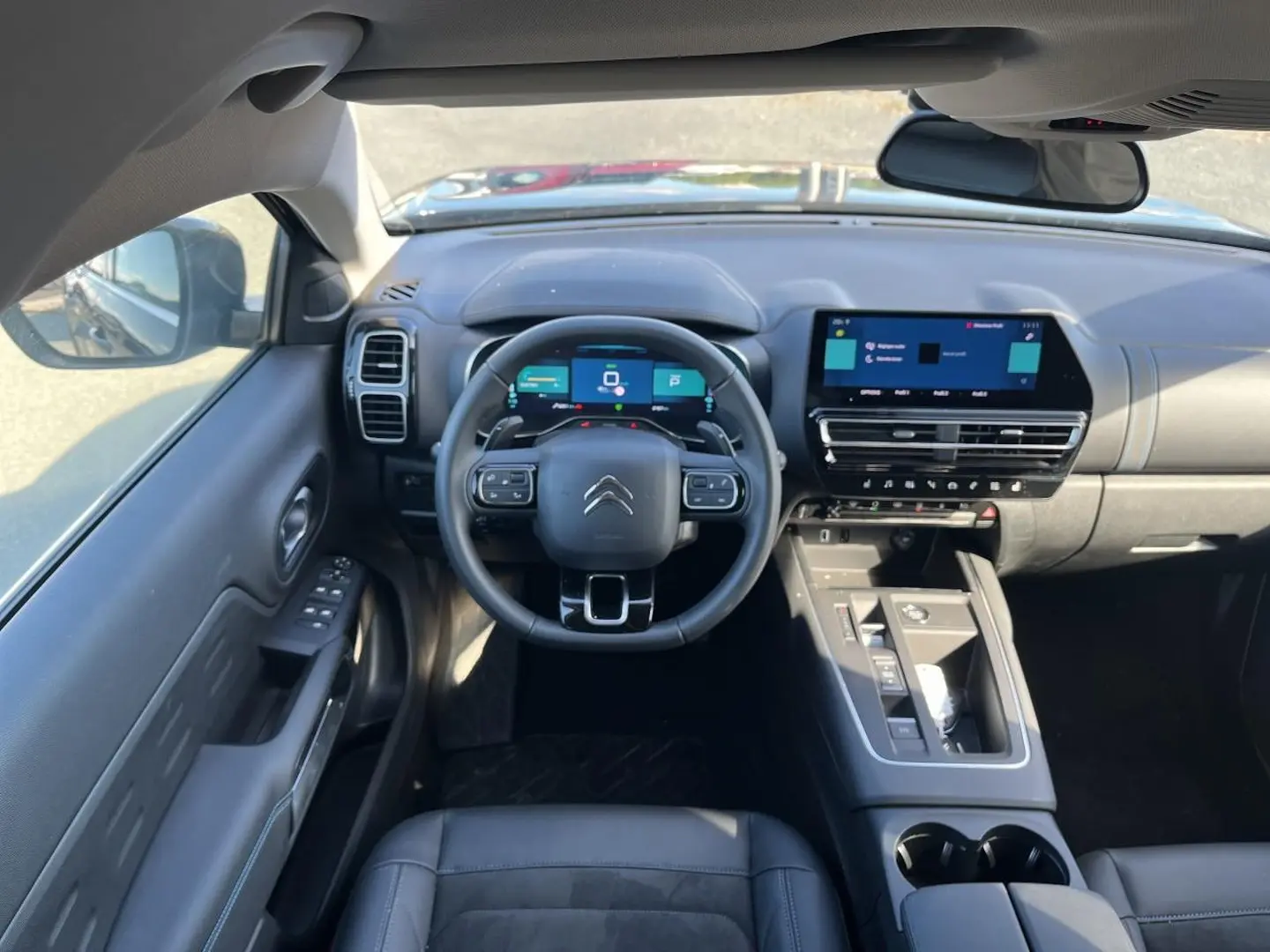 Vue intérieure avant du Citroën C5 Aircross hybride 2024 noir, avec tableau de bord numérique et écran tactile central.