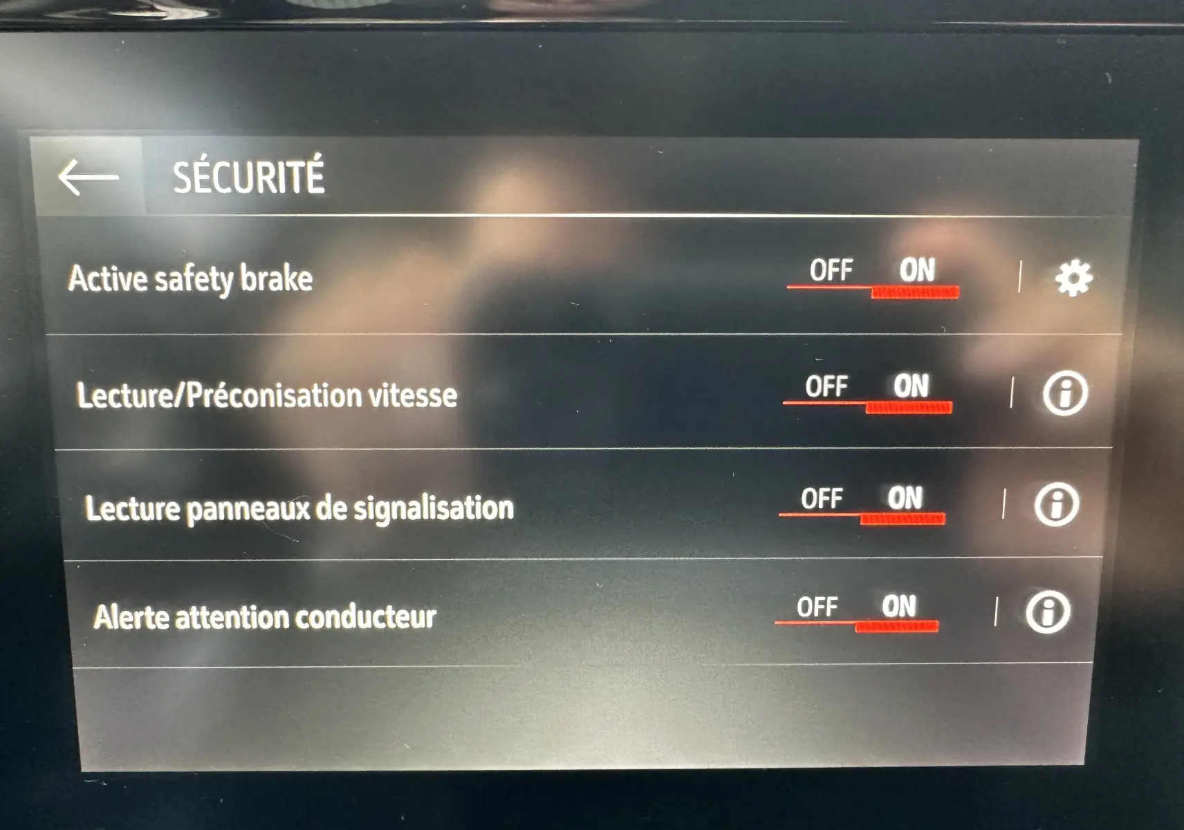 Écran tactile intérieur affichant les réglages de sécurité activés dans l'Opel Mokka rouge Kardinal 2021.