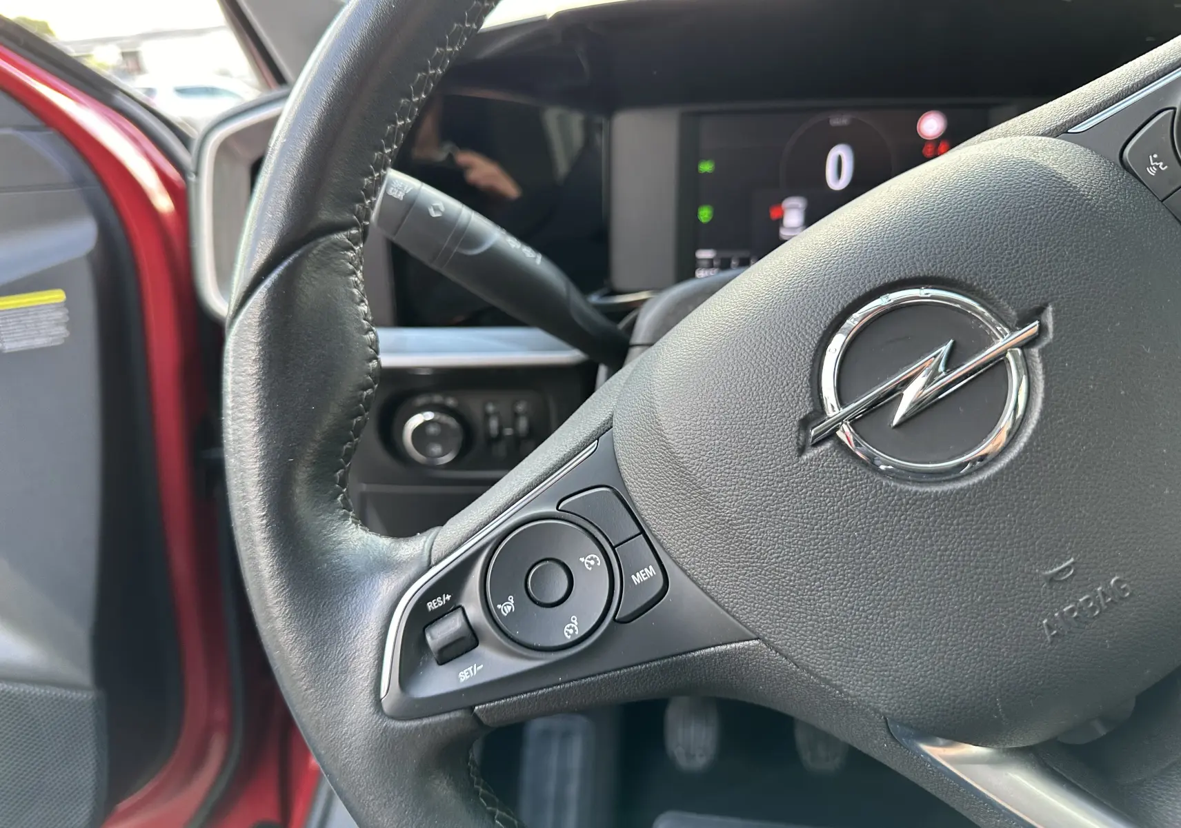 Gros plan sur le volant noir d'une Opel Mokka rouge Kardinal 2021, montrant les commandes au volant côté gauche.