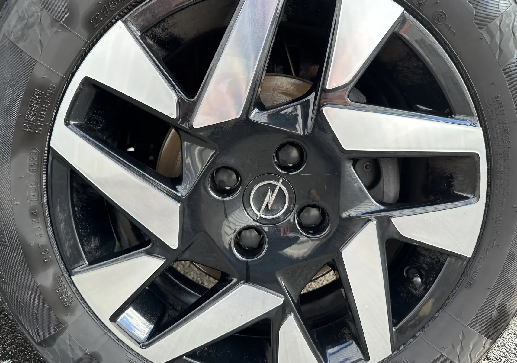 Gros plan sur la jante en alliage bicolore noir et argent avec logo Opel au centre du SUV Mokka rouge Kardinal.