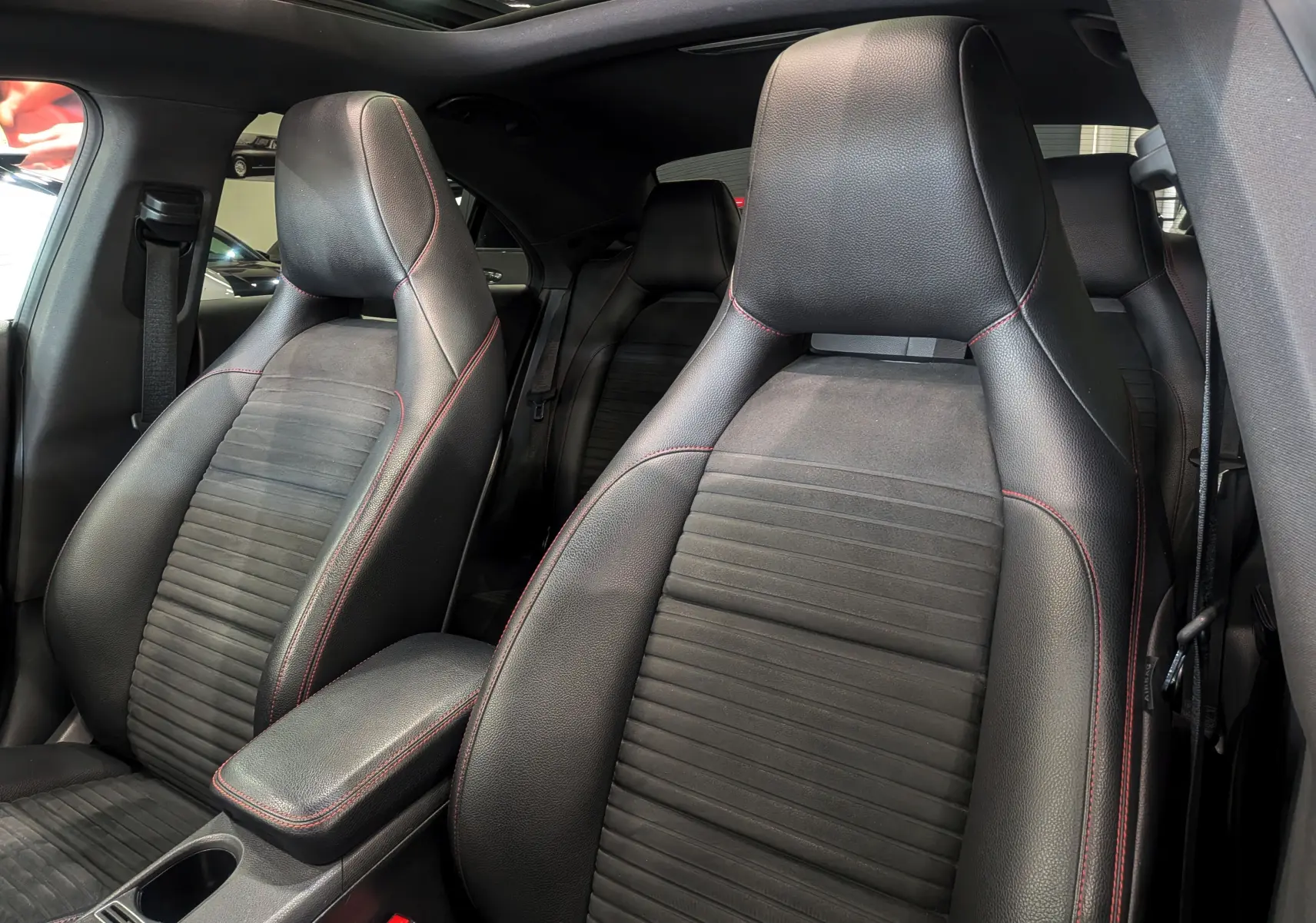Gros plan sur les sièges avant en cuir noir avec surpiqûres rouges de la Mercedes CLA 200 Fascination 2017.