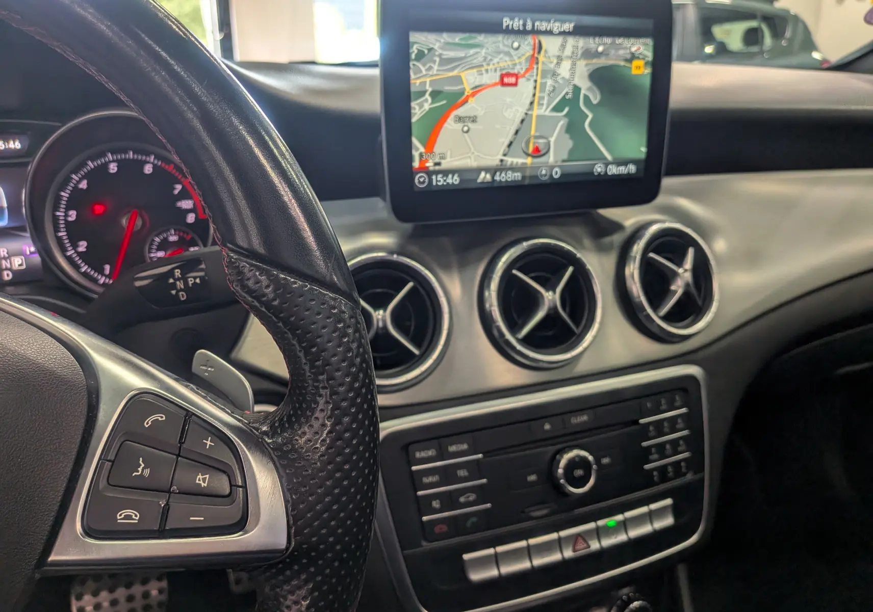 Vue intérieure de la Mercedes CLA 200 2017 montrant le volant, les commandes et l'écran de navigation central.