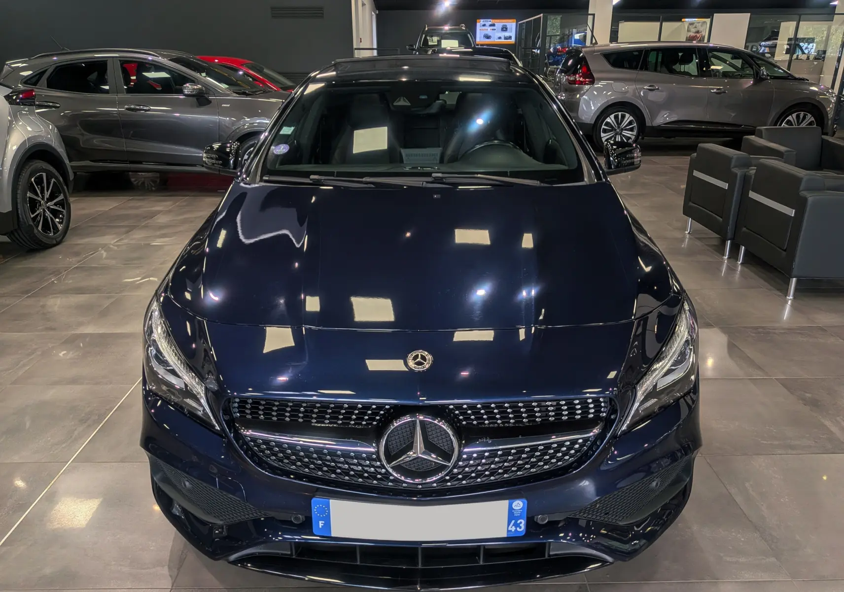 Vue frontale d'une Mercedes Classe CLA 200 Fascination en bleu Cavansite, avec calandre diamant et logo étoile au centre.