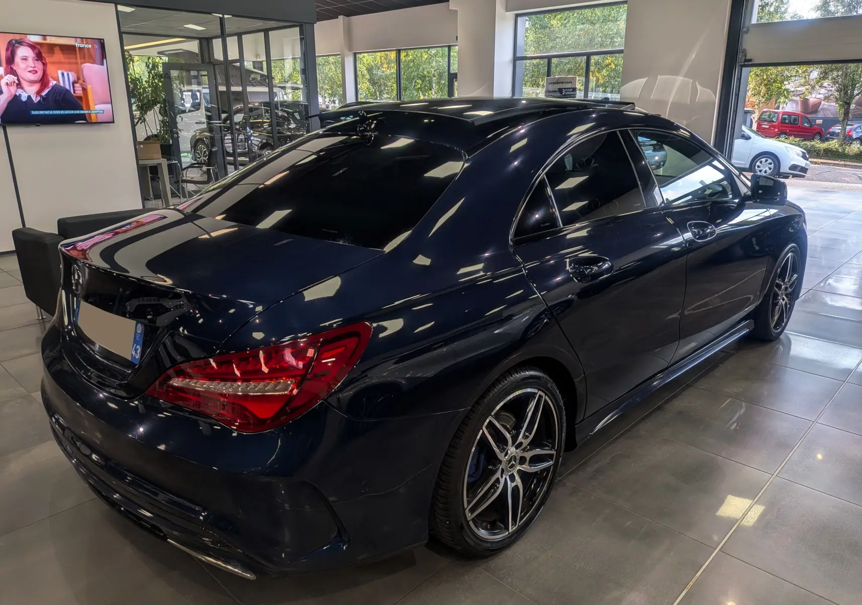 Mercedes Classe CLA 200 Fascination bleu Cavansite vue 3/4 arrière droit en showroom avec jantes AMG bicolores.