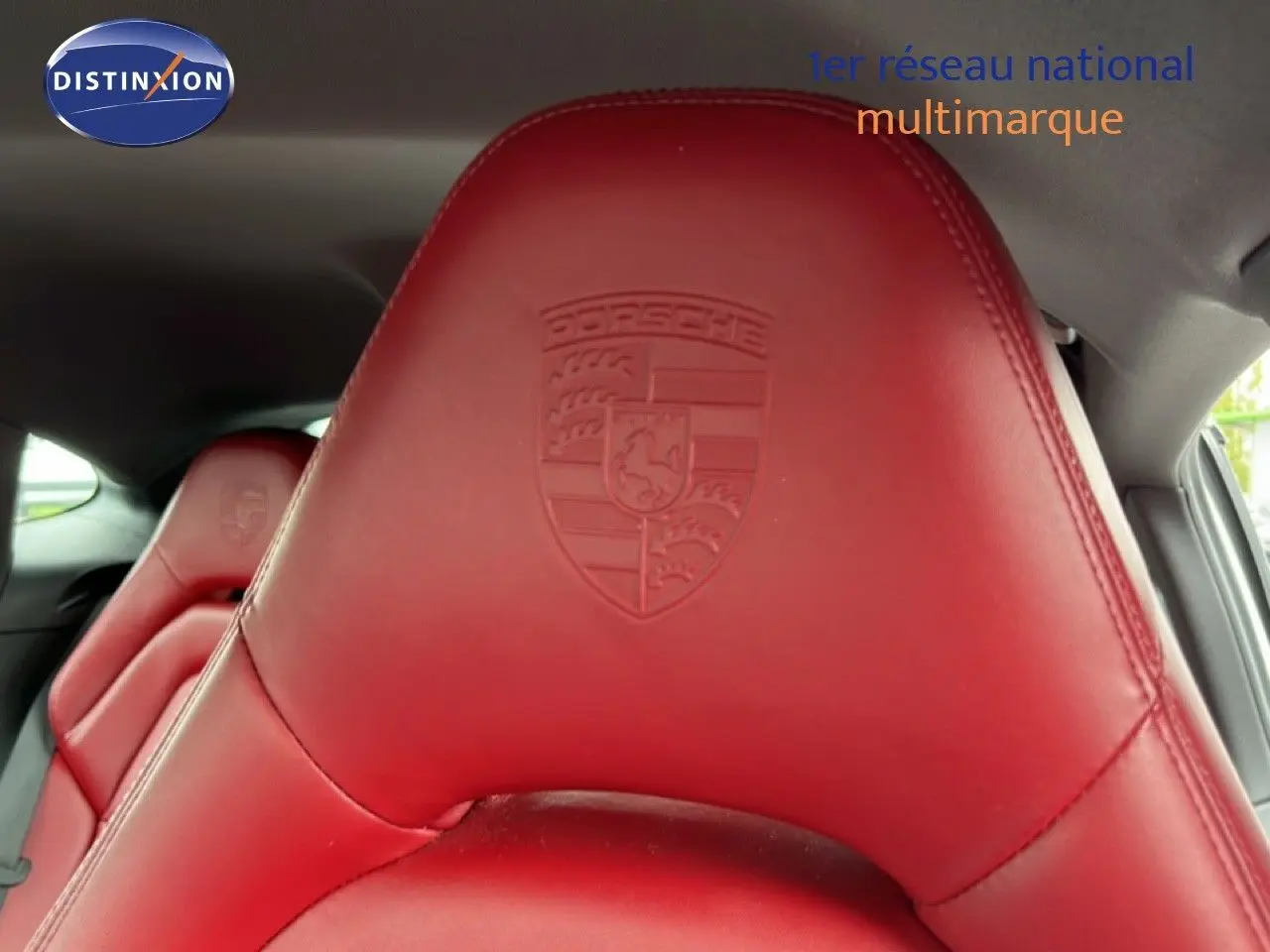 Gros plan sur l'appui-tête en cuir rouge embossé du logo Porsche à l'intérieur d'une Panamera 4 E-Hybrid blanche.