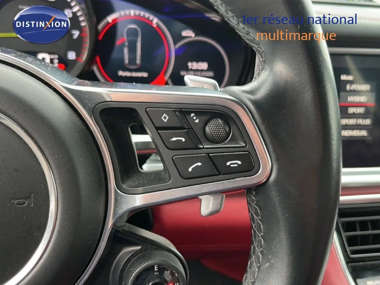 Gros plan sur le volant multifonction en cuir noir de la Porsche Panamera 4 E-Hybrid avec tableau de bord numérique rouge.