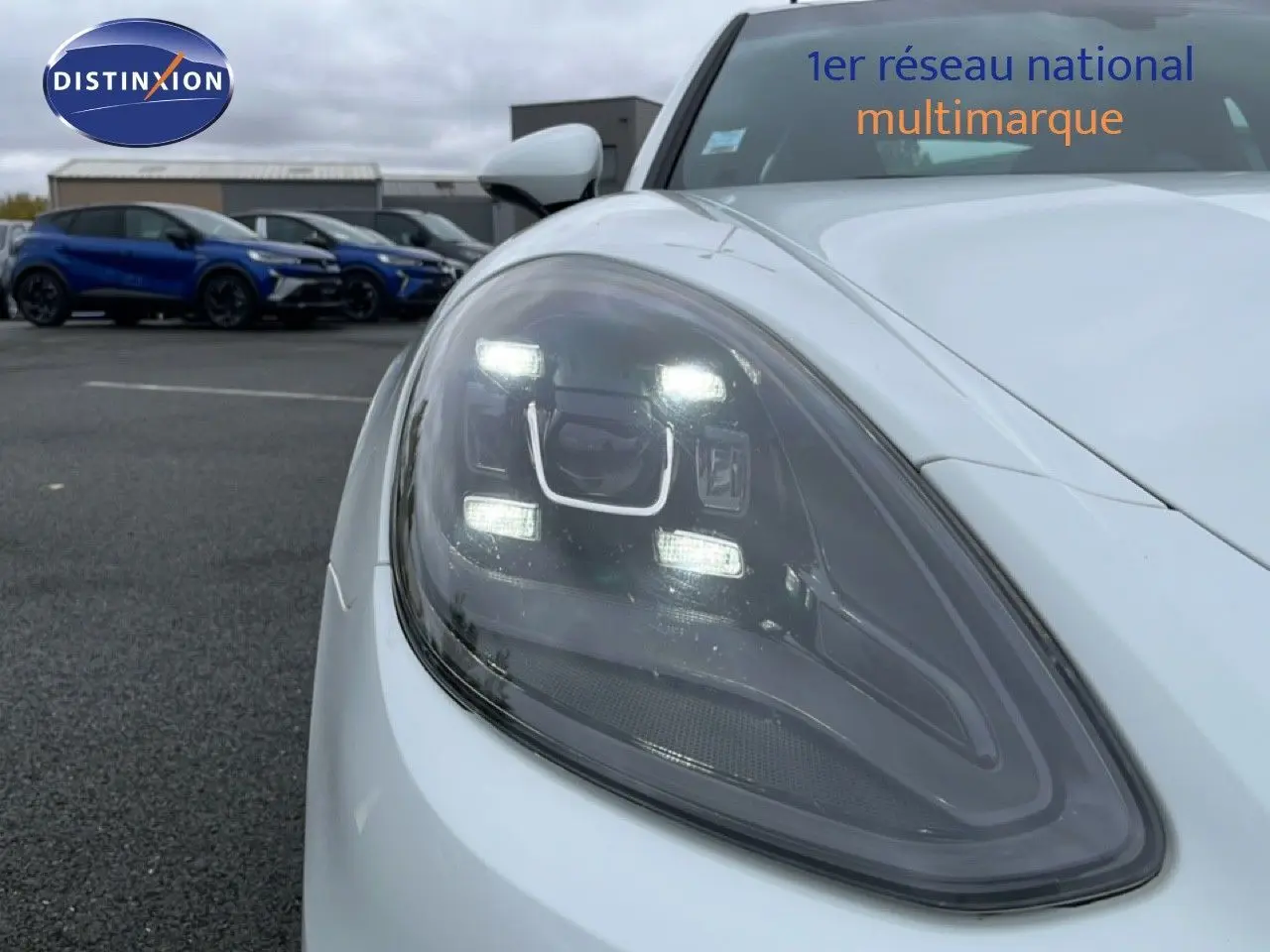 Gros plan sur le phare avant gauche allumé d'une Porsche Panamera 4 E-Hybrid blanche de 2017.