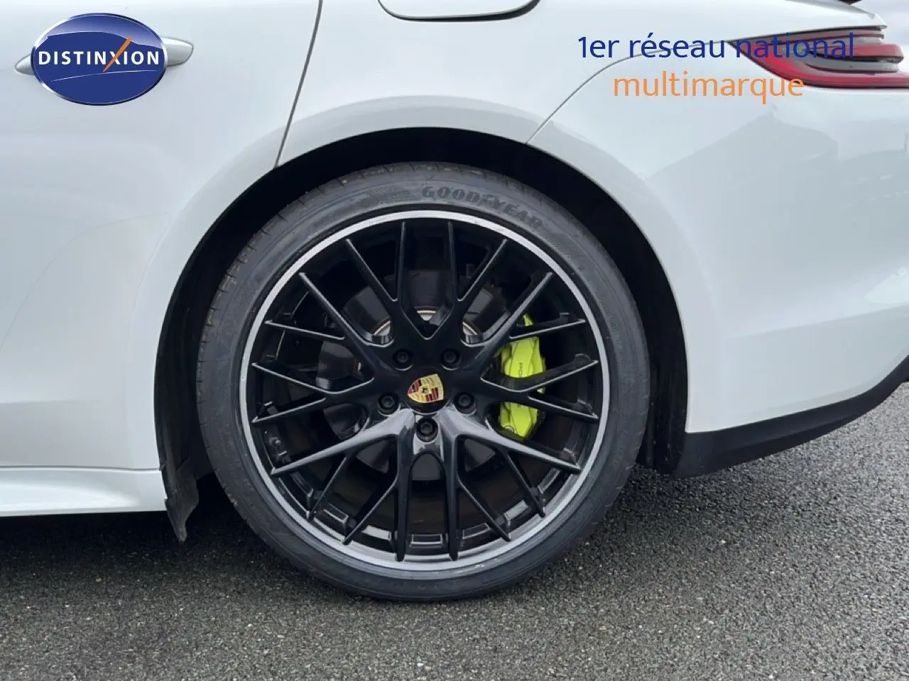 Gros plan sur la roue arrière droite noire brillante avec étrier de frein vert fluo d'une Porsche Panamera 4 E-Hybrid blanche.