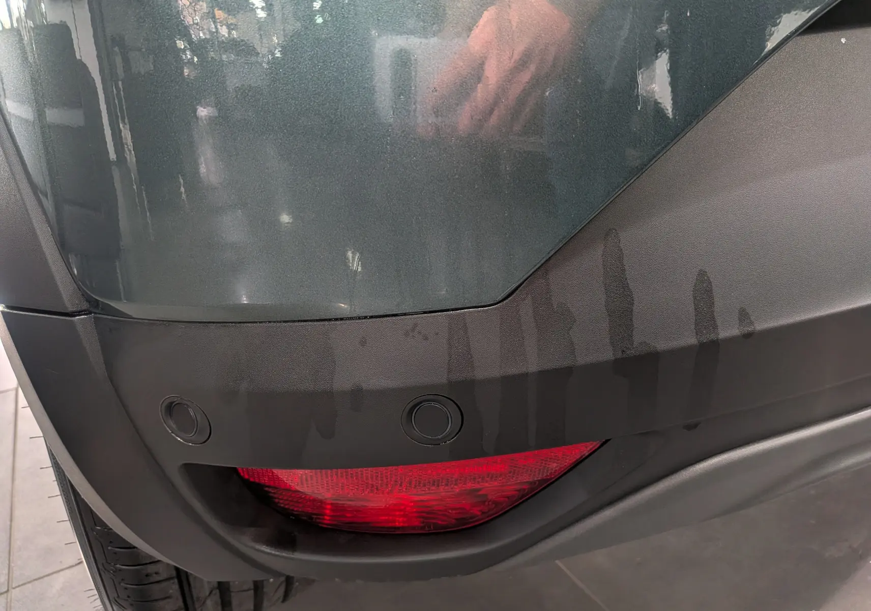 Gros plan sur le feu arrière droit rouge et le pare-chocs vert cèdre du Dacia Sandero Stepway TCe 110 CH Extreme 2025.