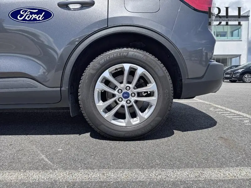 Gros plan sur la roue arrière droite du Ford Kuga gris Magnetic Métallisé avec jante alu et logo Ford au centre.