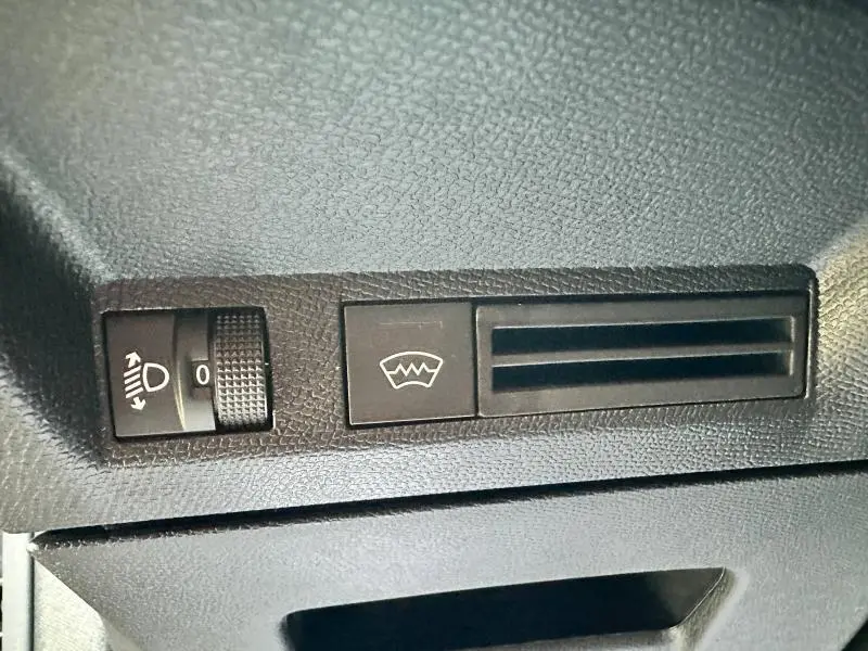 Détail du tableau de bord noir du Peugeot 3008 2025 montrant les commandes de réglage des phares et du dégivrage.