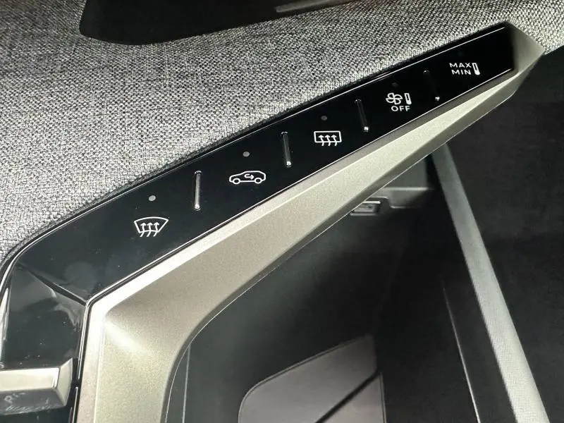 Gros plan sur les commandes tactiles de climatisation intégrées dans l’intérieur gris tissu du Peugeot 3008 Hybrid 2025.