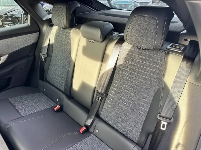 Vue rapprochée des sièges arrière gris tissu et cuir du Peugeot 3008 1.2 Hybrid 136ch Allure 2025 en lumière naturelle.