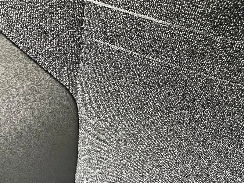 Gros plan sur le tissu CRISPY gris texturé et le revêtement noir TEP de la banquette arrière du Peugeot 3008 hybride.
