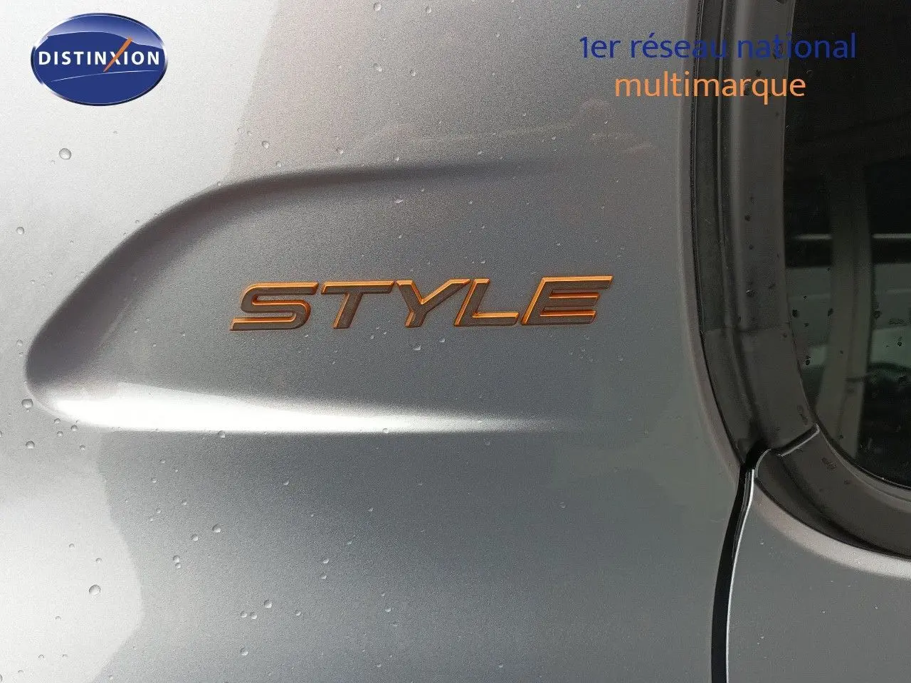 Détail de l’inscription STYLE en orange sur la porte arrière droite d’une Peugeot 208 gris Artense métal.