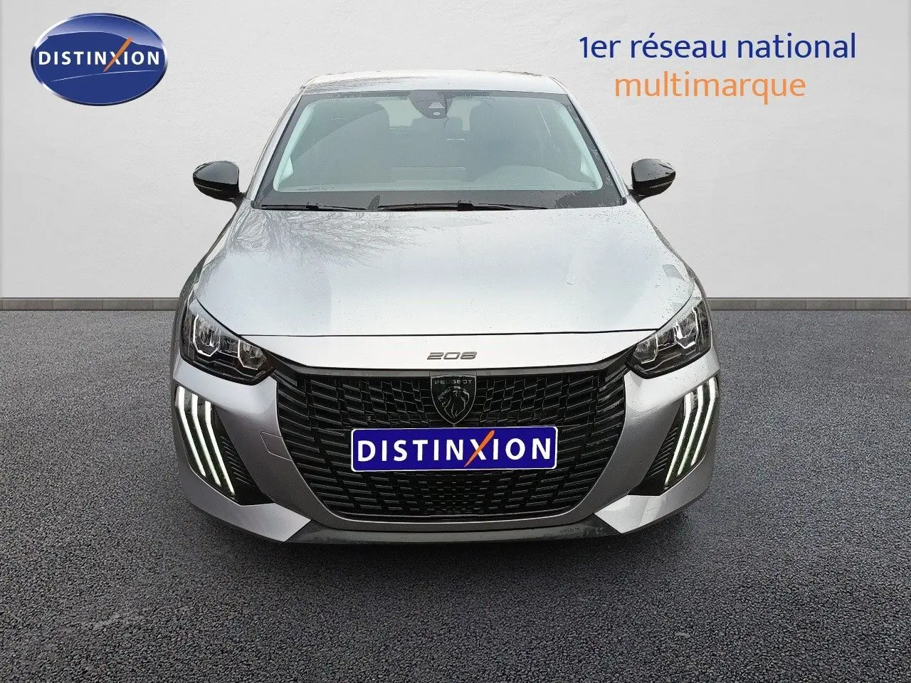 Vue frontale d’une Peugeot 208 gris Artense métal avec calandre noire et feux diurnes LED en griffes distinctives.