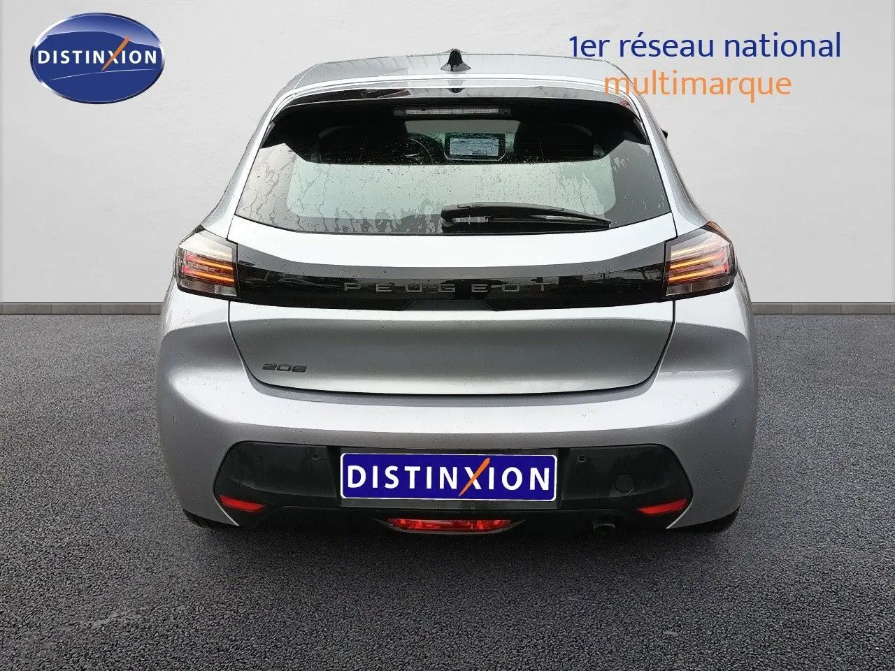 Vue arrière d'une Peugeot 208 gris Artense métal 2025 avec feux LED et hayon fermé sur sol goudronné.