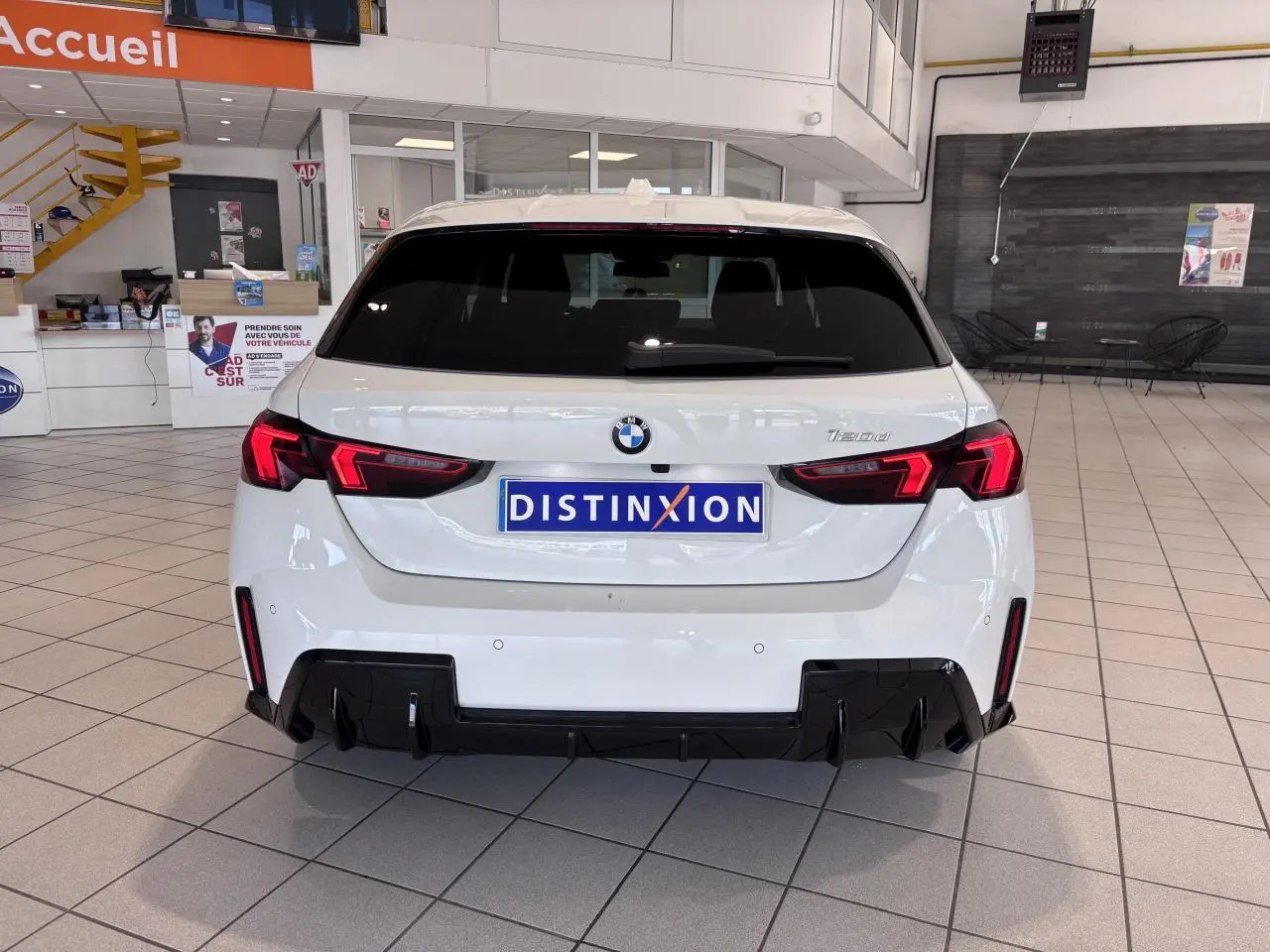 Vue arrière d'une BMW Série 1 120d M Sport blanche de 2025, avec feux arrière LED et diffuseur noir sportif.