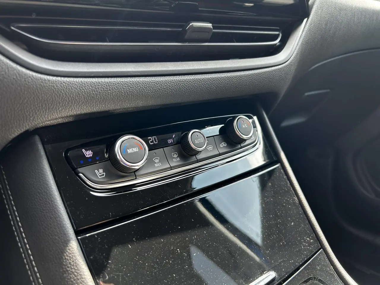 Gros plan sur la console centrale noire brillante avec commandes de climatisation de l'Opel Grandland 1.6 Hybrid 2022.