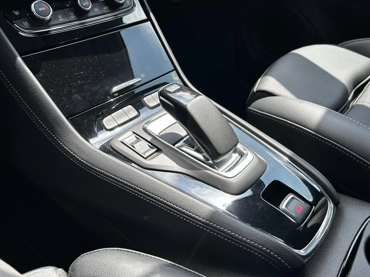 Gros plan sur la console centrale noire brillante de l’Opel Grandland 1.6 Hybrid avec levier de vitesse automatique et sièges cuir noirs.