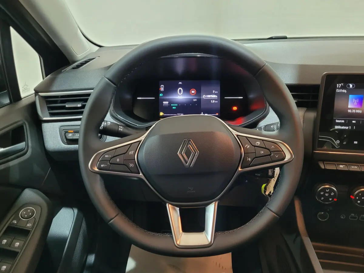 Vue centrée sur le volant cuir noir de la Renault Clio 2025 avec tableau de bord numérique et écran tactile à droite.