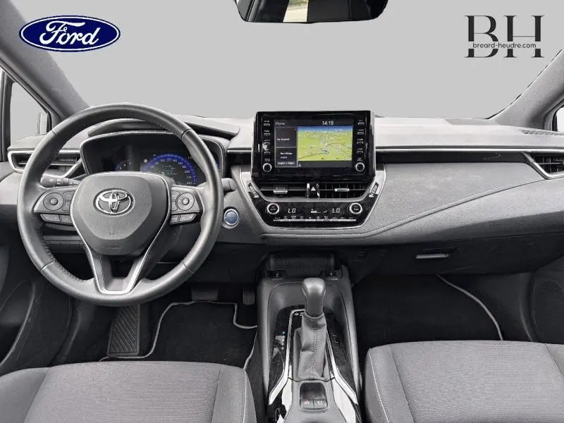 Vue intérieure frontale du tableau de bord de la Toyota Corolla gris Manhattan, avec écran tactile GPS et volant multifonction cuir.