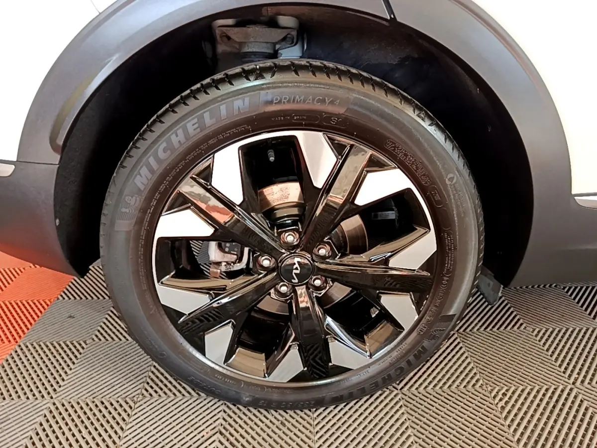 Gros plan sur la roue avant droite du KIA SPORTAGE blanc, jante alliage noir brillant avec pneus Michelin.