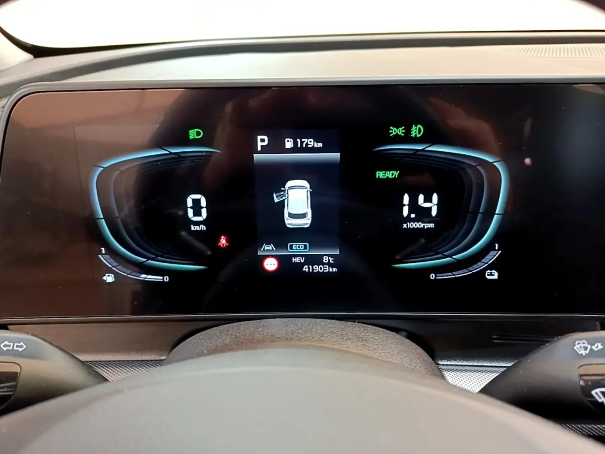 Tableau de bord numérique du Kia Sportage blanc, affichage central avec vitesse, régime et alertes visibles.