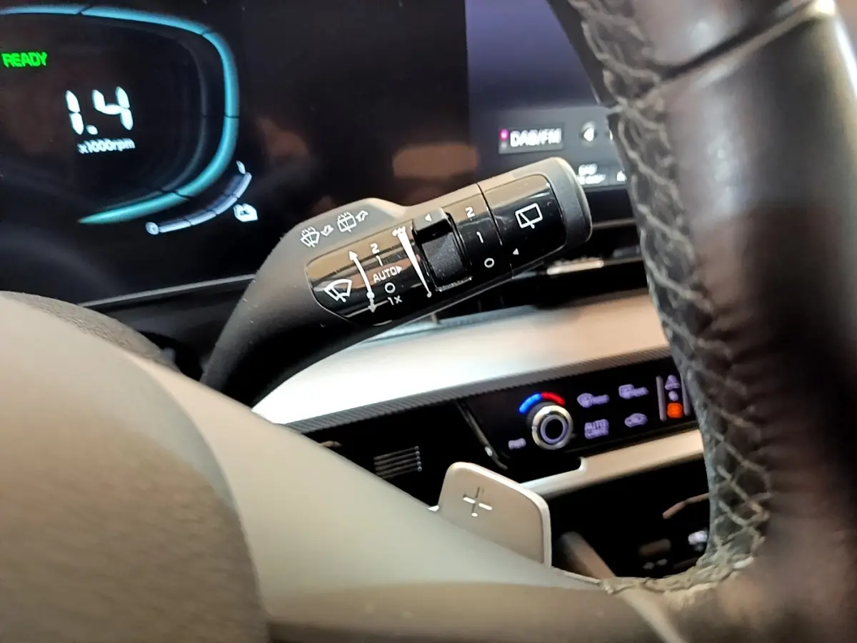 Gros plan sur le commodo d’essuie-glace et le volant cuir du tableau de bord du Kia Sportage blanc hybride rechargeable 2022.