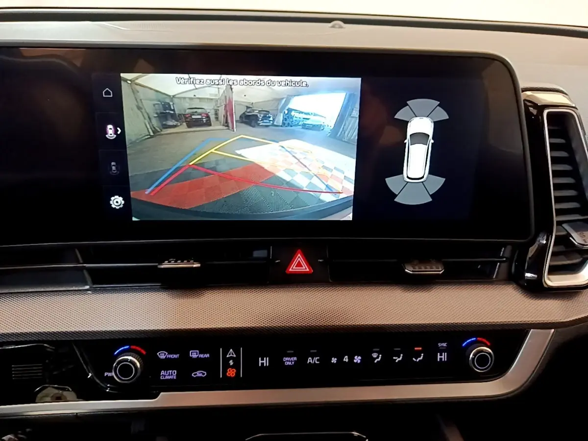 Vue rapprochée de l'écran tactile central du Kia Sportage blanc 2022 montrant l'aide au stationnement arrière.