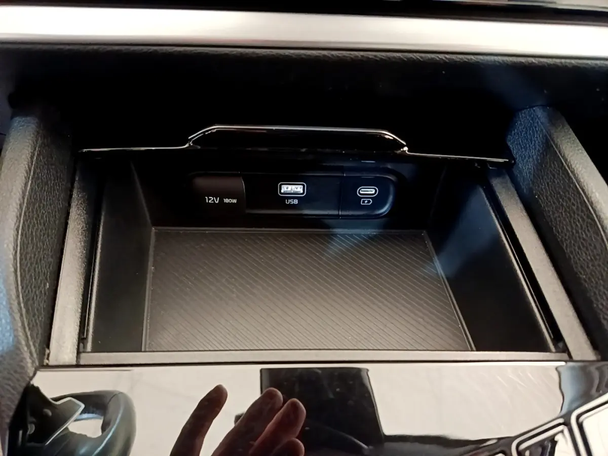 Vue rapprochée de la console centrale noire du Kia Sportage 2022 montrant les prises USB et 12V intégrées.