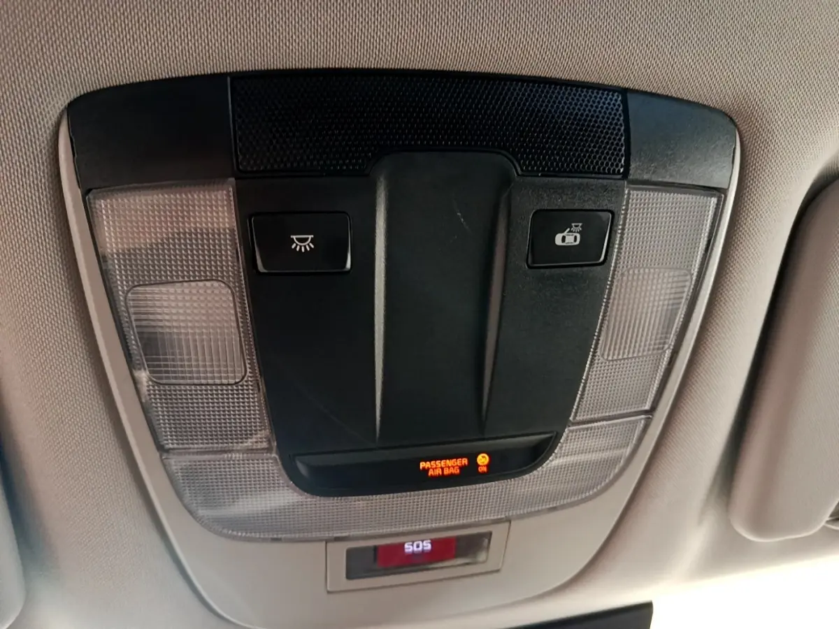 Vue intérieure du plafonnier avec commandes d’éclairage et indicateur airbag passager allumé sur Kia Sportage blanc 2022.