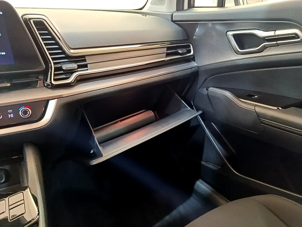 Intérieur du Kia Sportage 2022, vue côté passager sur la boîte à gants ouverte et tableau de bord noir.