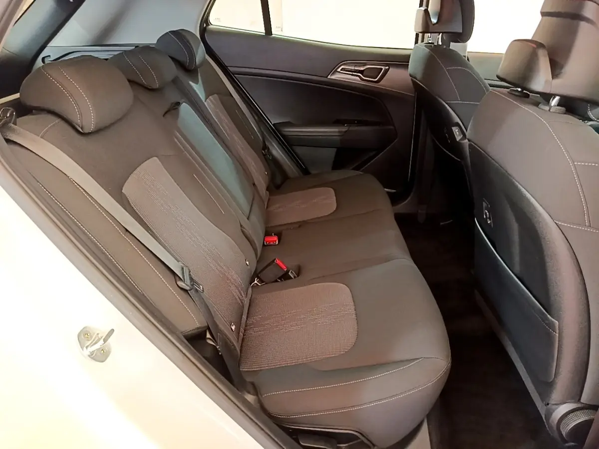 Vue intérieure côté gauche des sièges arrière en tissu gris du KIA Sportage blanc 2022, avec ceintures et appuie-têtes visibles.