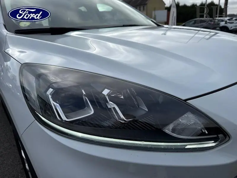 Gros plan sur le phare avant gauche du Ford Kuga blanc Glacier, mettant en valeur son design LED moderne.