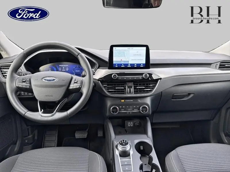 Vue intérieure avant du Ford Kuga blanc Glacier 2021, montrant le volant cuir multifonction et l’écran tactile central.