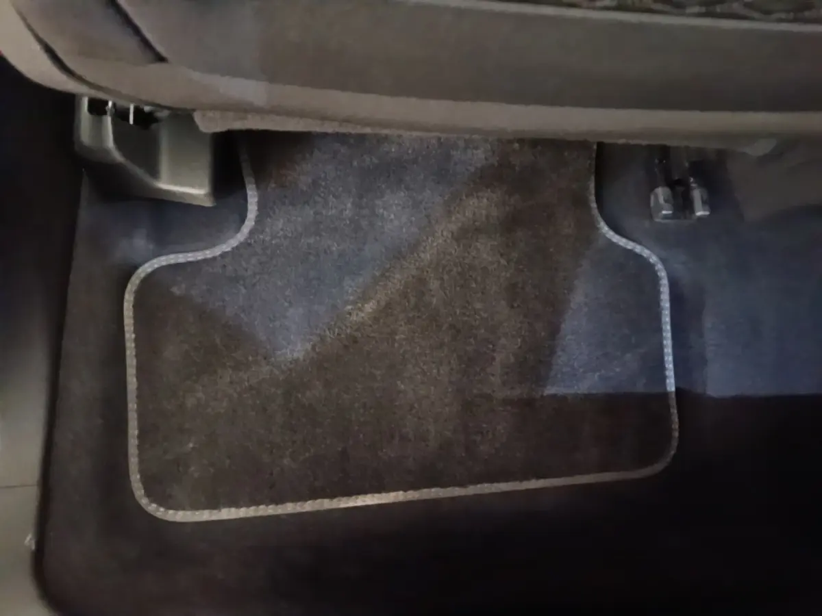 Vue rapprochée du tapis de sol noir côté passager arrière du DS7 Crossback E-TENSE 225 BUSINESS gris foncé.
