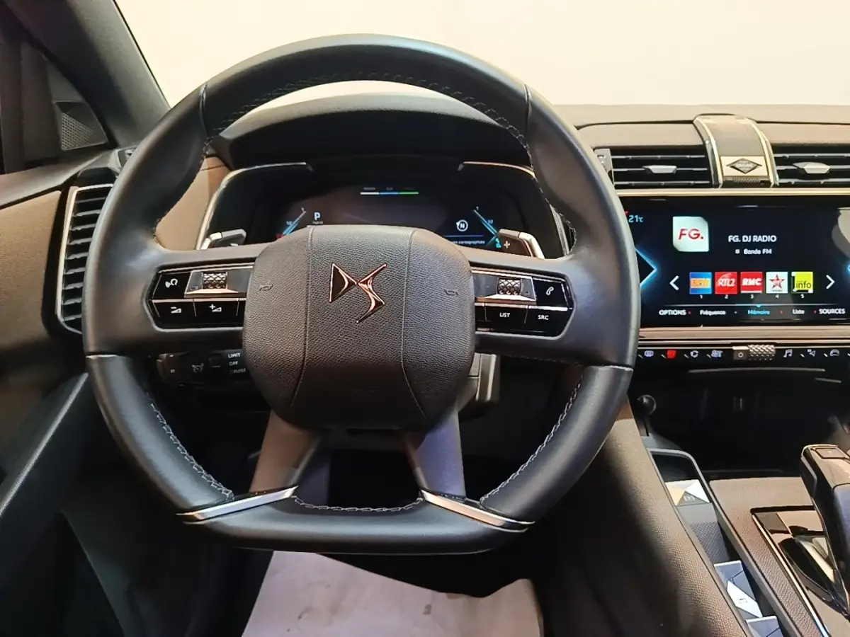 Vue frontale du volant cuir noir DS d’un DS7 Crossback E-TENSE 225 BUSINESS avec tableau de bord numérique et écran tactile.