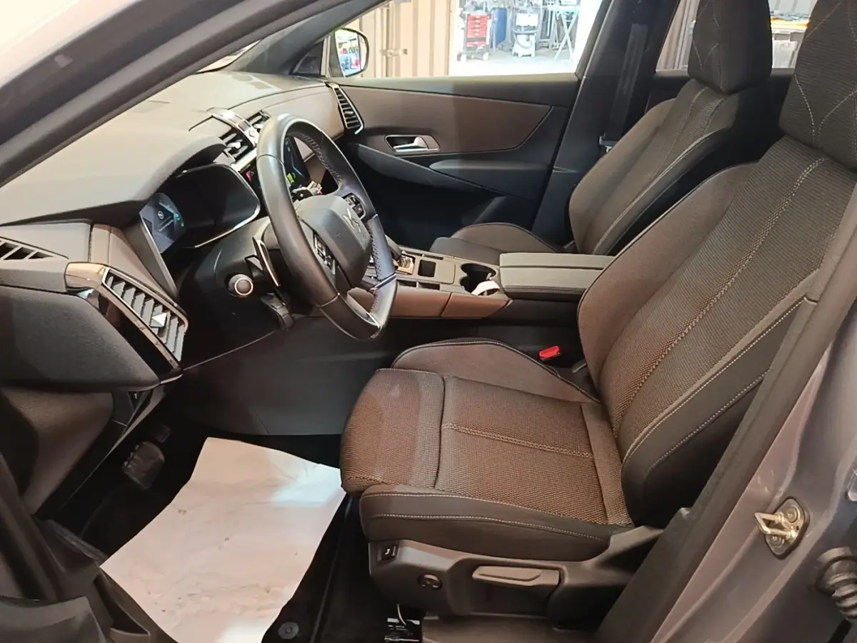 Intérieur avant droit du DS7 Crossback gris foncé, sièges tissu, volant cuir multifonctions et tableau de bord moderne.