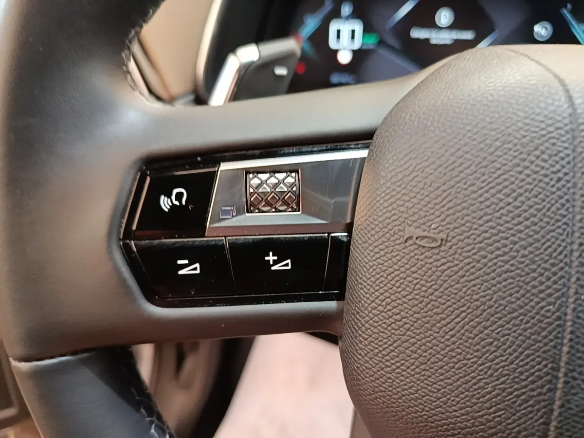 Gros plan sur le volant cuir multifonctions du DS7 Crossback E-TENSE 225 Business, avec commandes de volume et reconnaissance vocale.