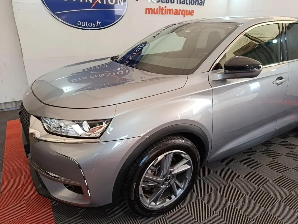 Vue 3/4 avant droit du DS7 Crossback E-TENSE 225 Business gris foncé, avec jantes alliage et phares LED distinctifs.