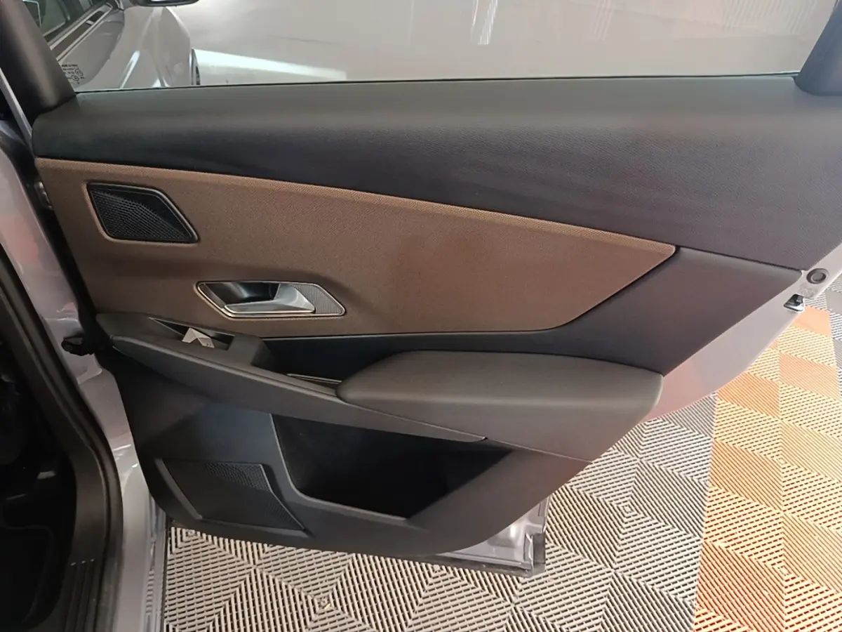 Vue intérieure de la porte arrière gauche du DS7 Crossback gris foncé, avec habillage bicolore marron et noir.