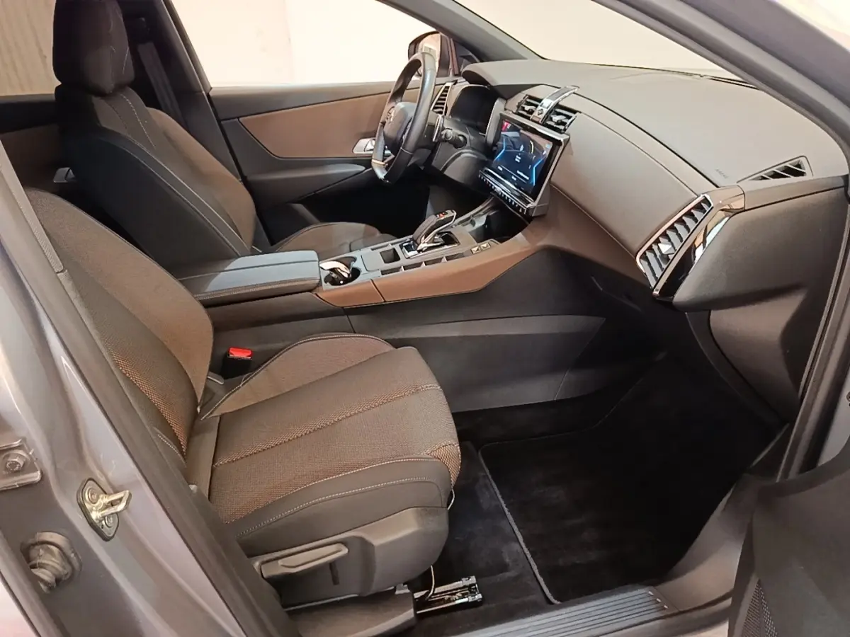 Vue intérieure côté passager avant du DS7 Crossback E-TENSE 225 Business avec sièges tissu gris et tableau de bord moderne.