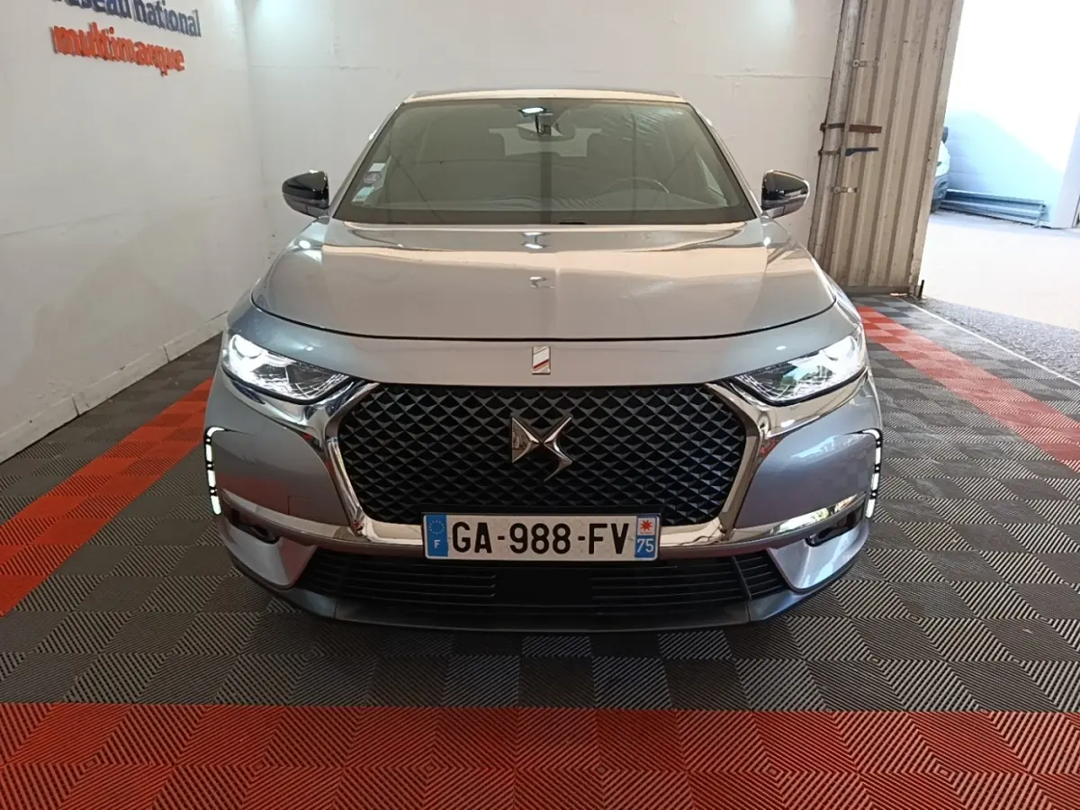 Vue avant d'un DS7 Crossback gris foncé avec calandre distinctive et feux LED allumés en intérieur.