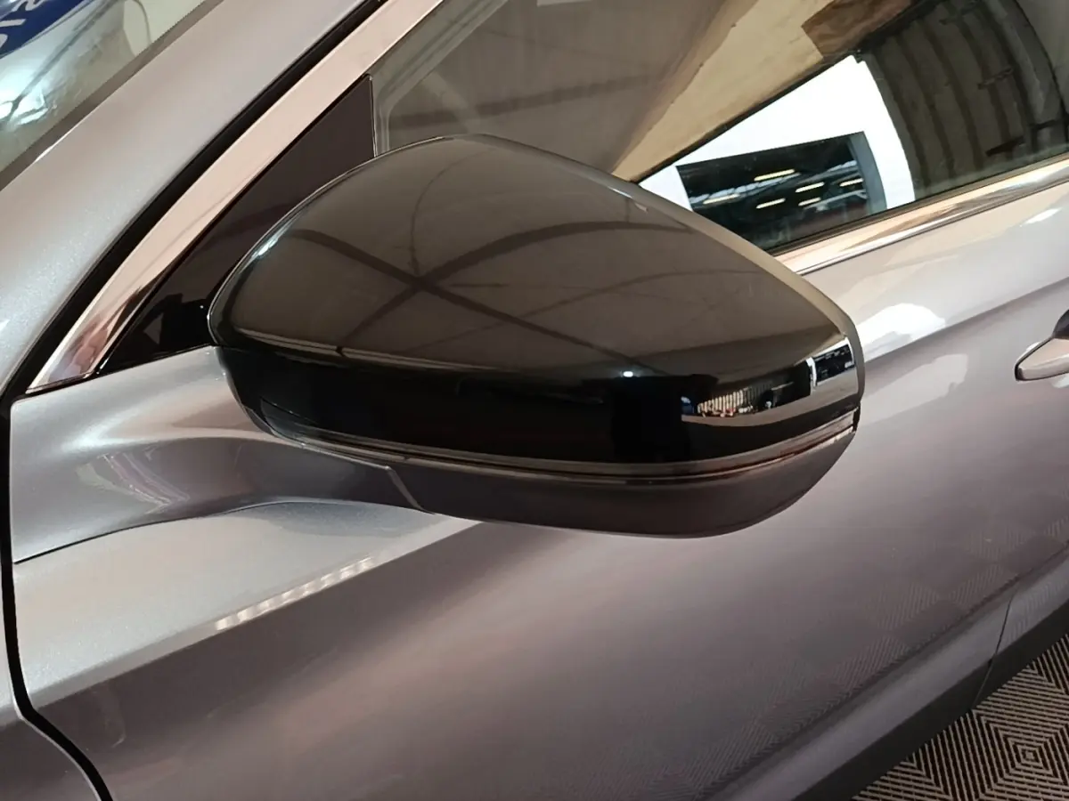 Rétroviseur extérieur noir en gros plan sur le côté gauche d’un DS7 Crossback gris foncé hybride rechargeable.