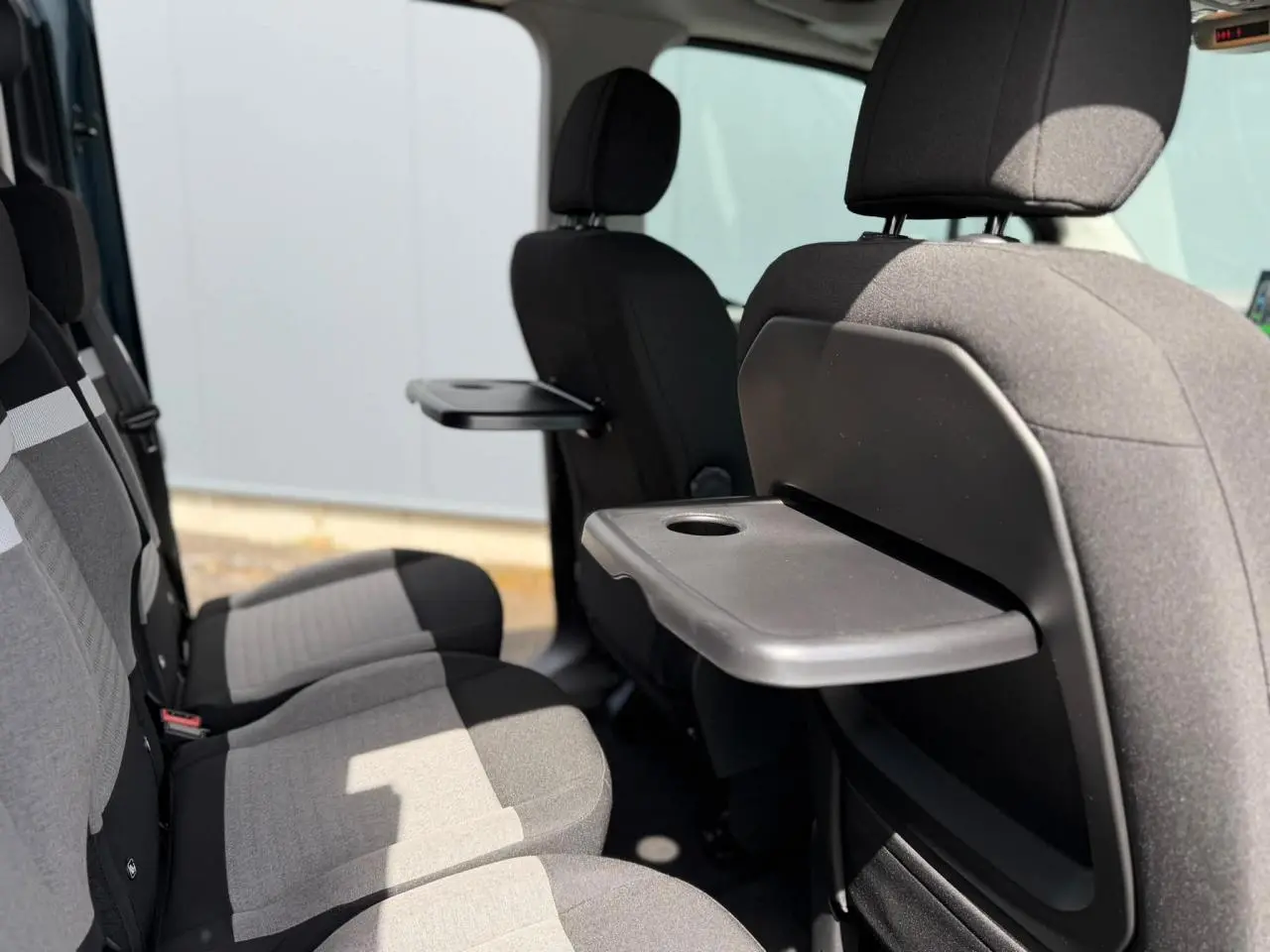Vue intérieure côté droit des sièges arrière gris avec tablettes rabattables sur les dossiers avant du Citroën Berlingo Multispace.